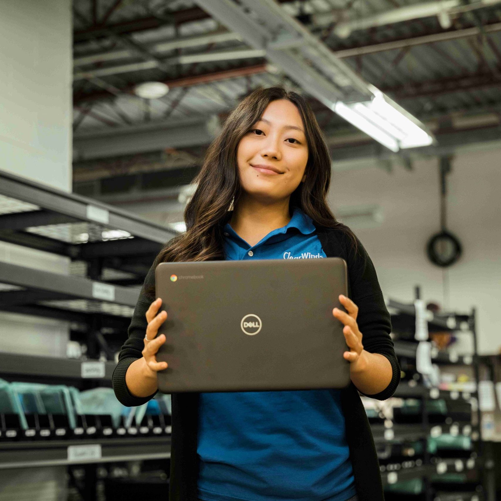 A Clear Winds device repair technician holding a Chromebook.