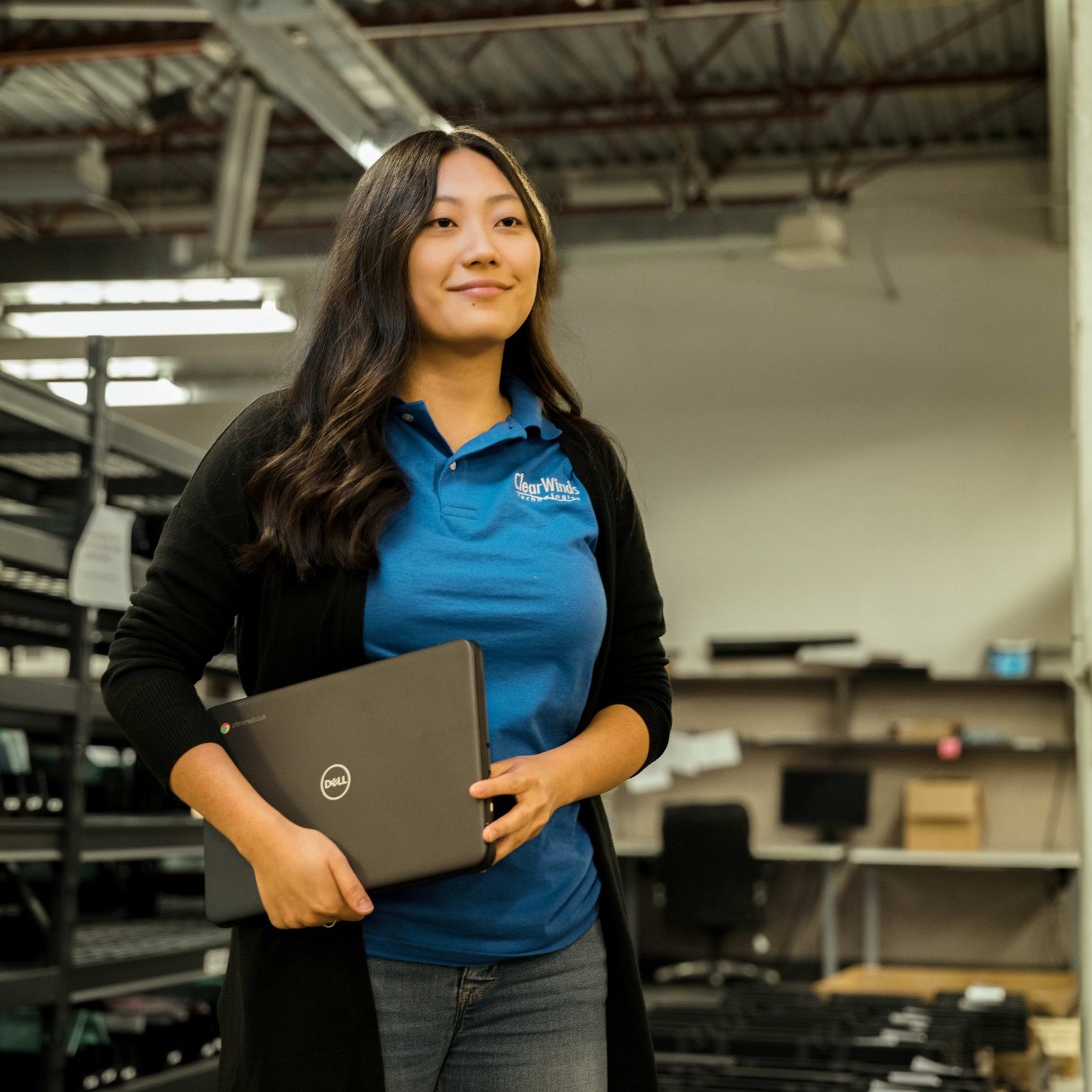 A member of the Clear Winds device repair team holding a Dell Chromebook.