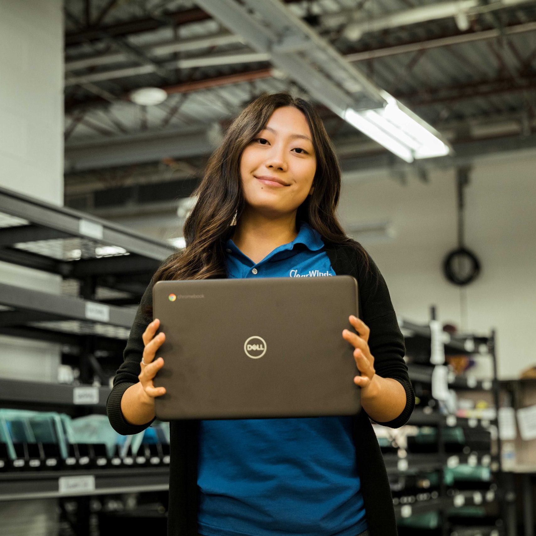 A member of the Clear Winds repair team holding a Dell Chromebook.